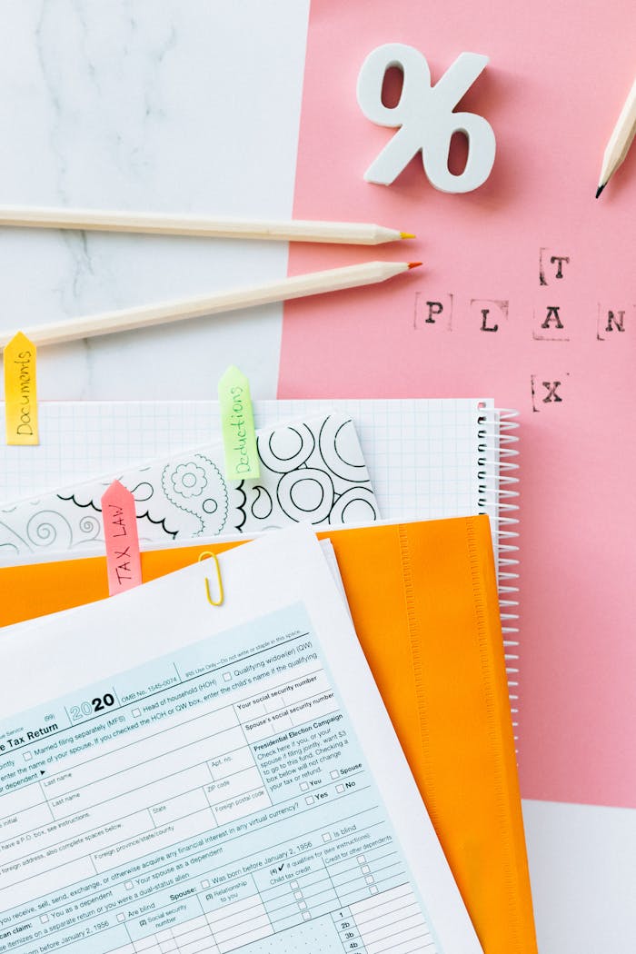 about-us Overhead view of tax documents, percentage sign, and stationery items on pastel paper.