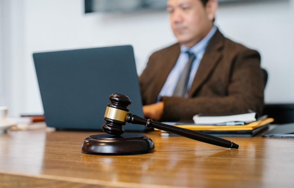 pexels photo 5668772 5668772 Crop concentrated Asian male judge in formal clothes sitting using modern netbook while working in law office