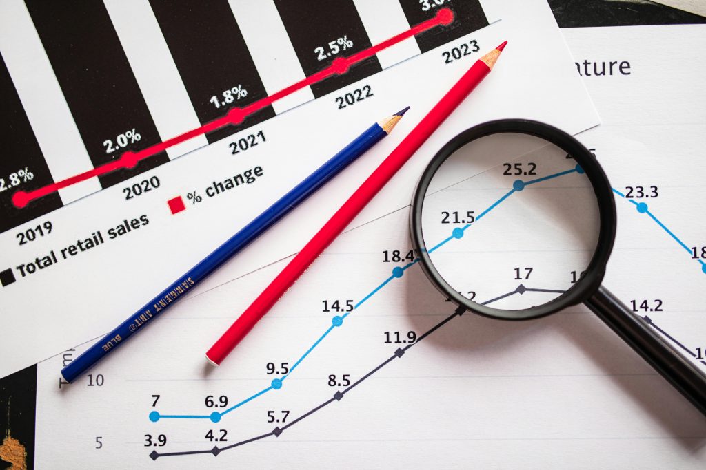 pexels photo 7948055 7948055 Magnifying glass and colored pencils on financial trend graphs highlighting sales growth.